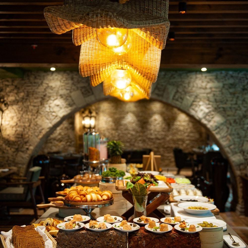 Close-up shot of the buffet table spread with well-plated dishes placed under the warm lighting from the unique chandelier at the Mila restaurant at The Evren, Vagator.