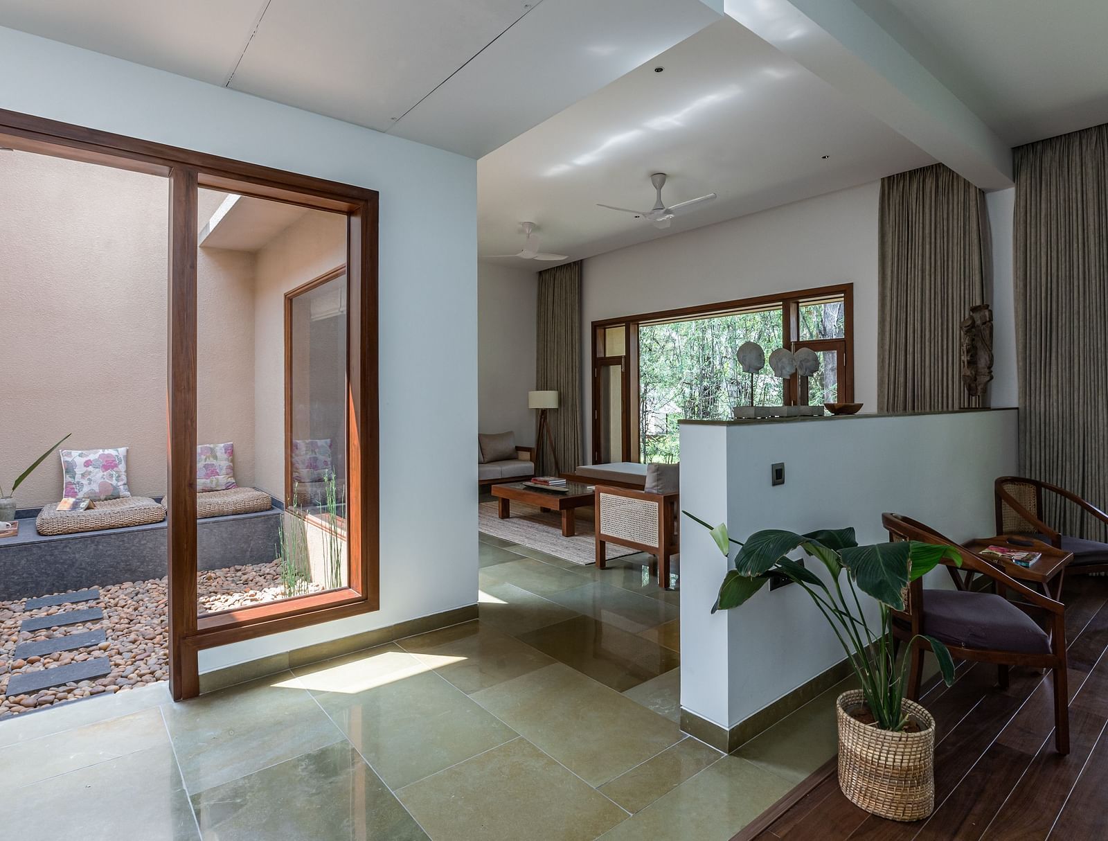 A room with sliding glass doors, a couch, and a view of a garden, bright interior - Shreyas Retreat