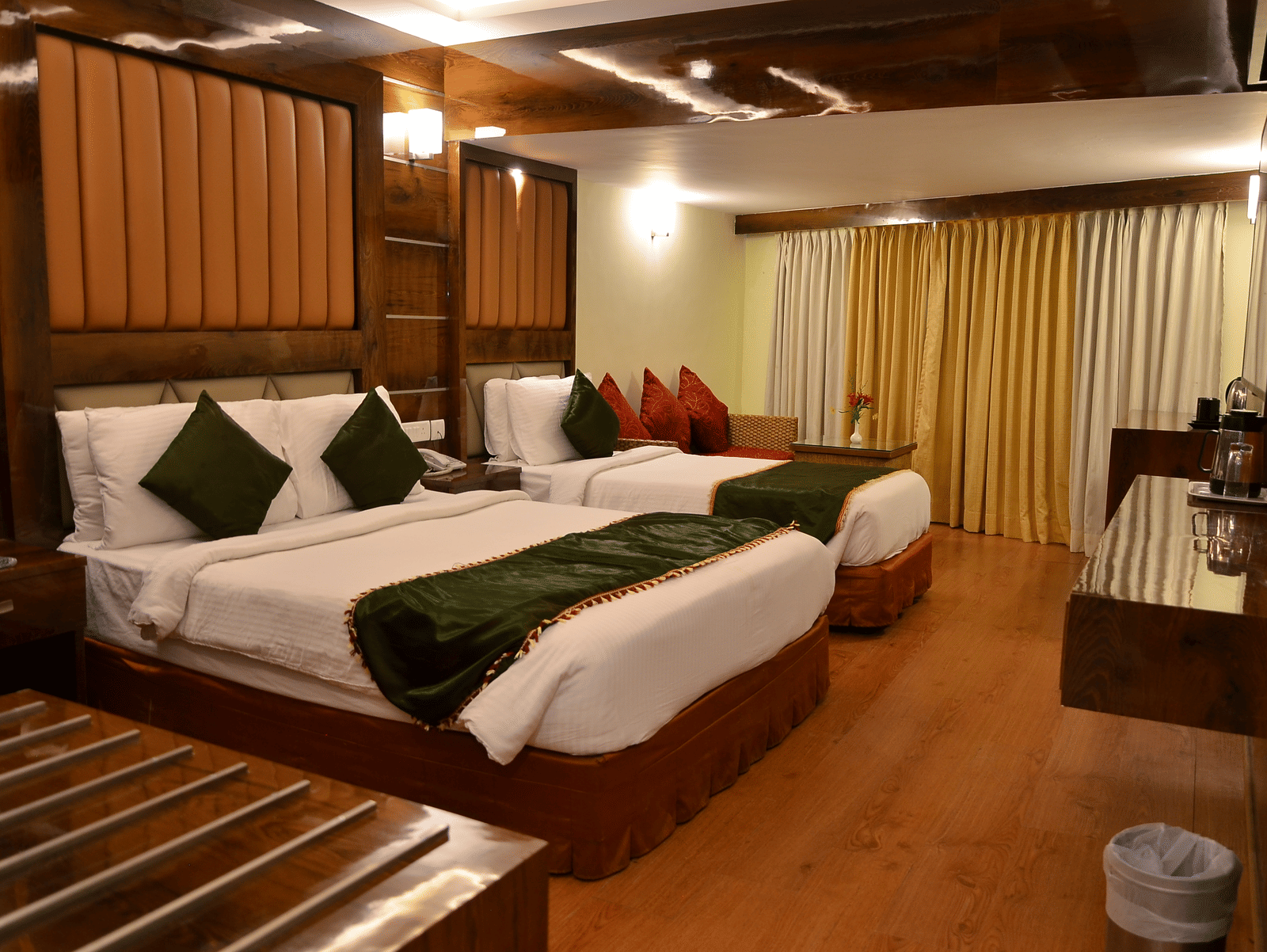 A large family room with two double beds, wooden furniture, and vibrant green cushions - Benzz Park, Kodaikanal