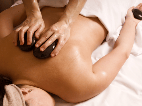 A person getting a hot stone massage while lying on her stomach at YO1 Longevity & Health Resort