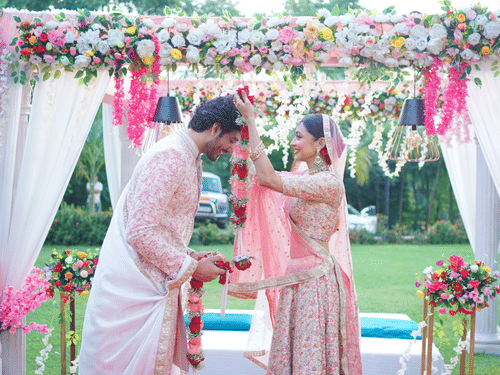 Couple exchanging rings under floral arch