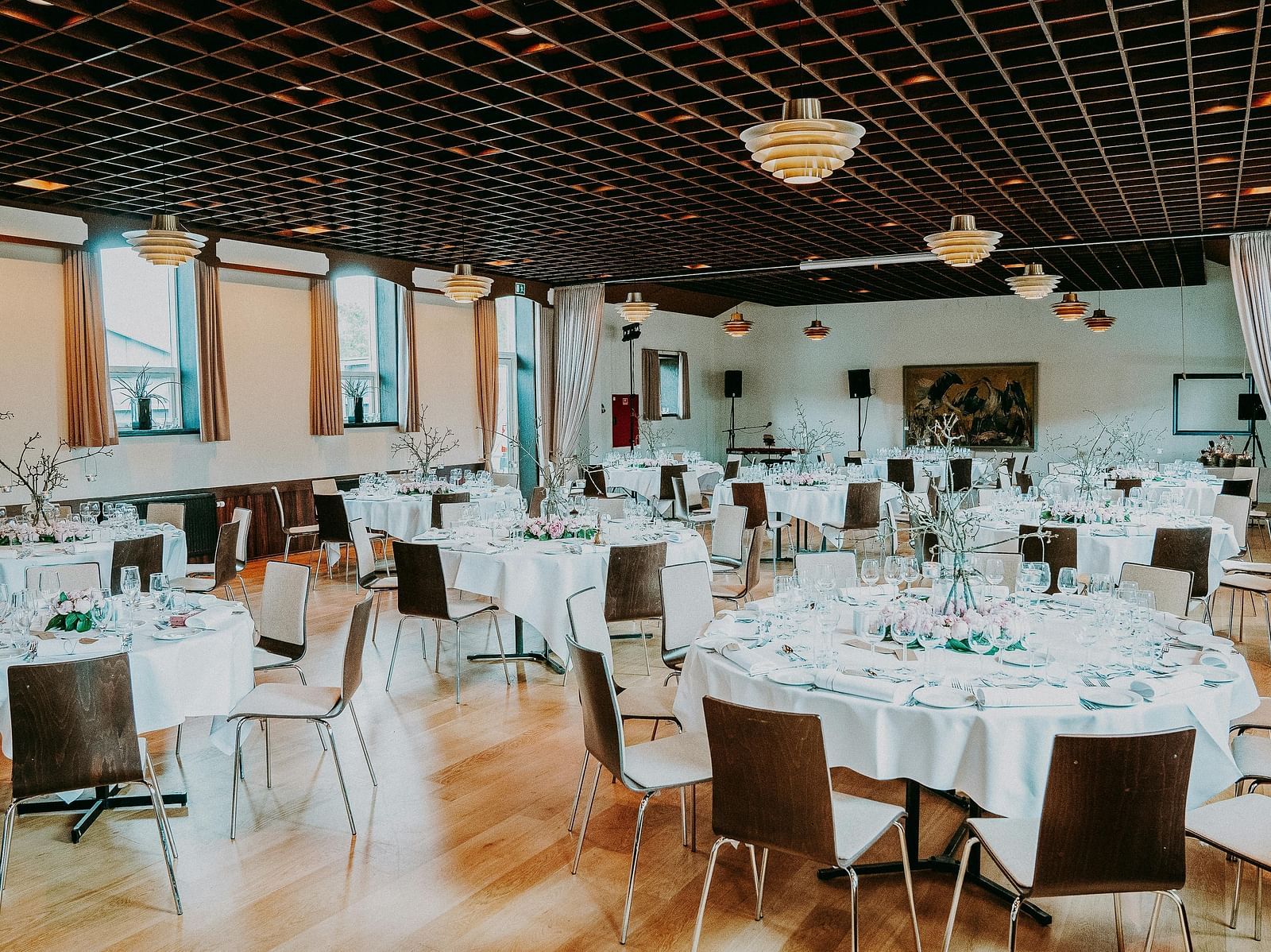 An elegantly set dining hall with round tables, white tablecloths and a modern decor