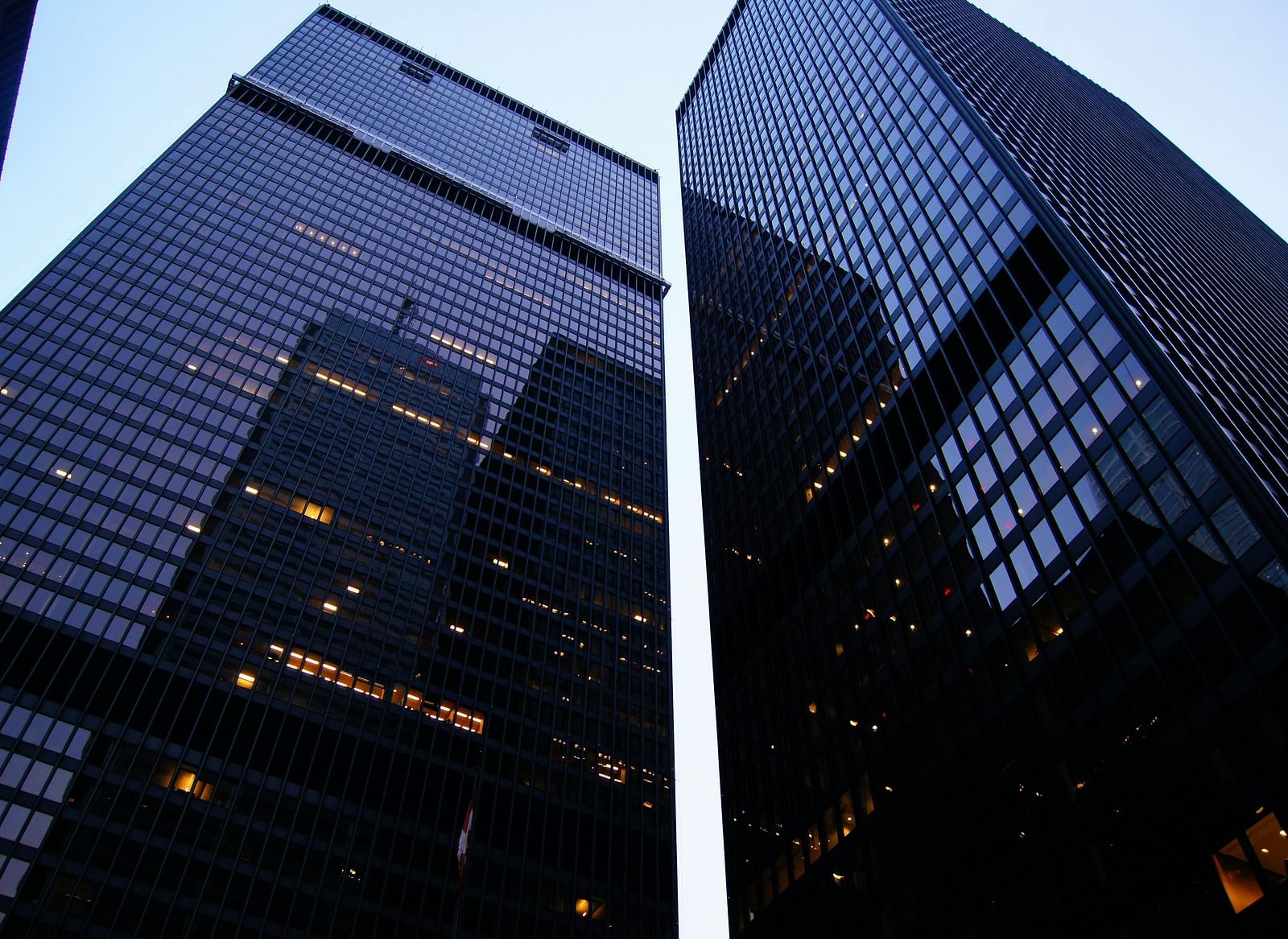 Two tall, dark skyscrapers against a clear, bright sky.