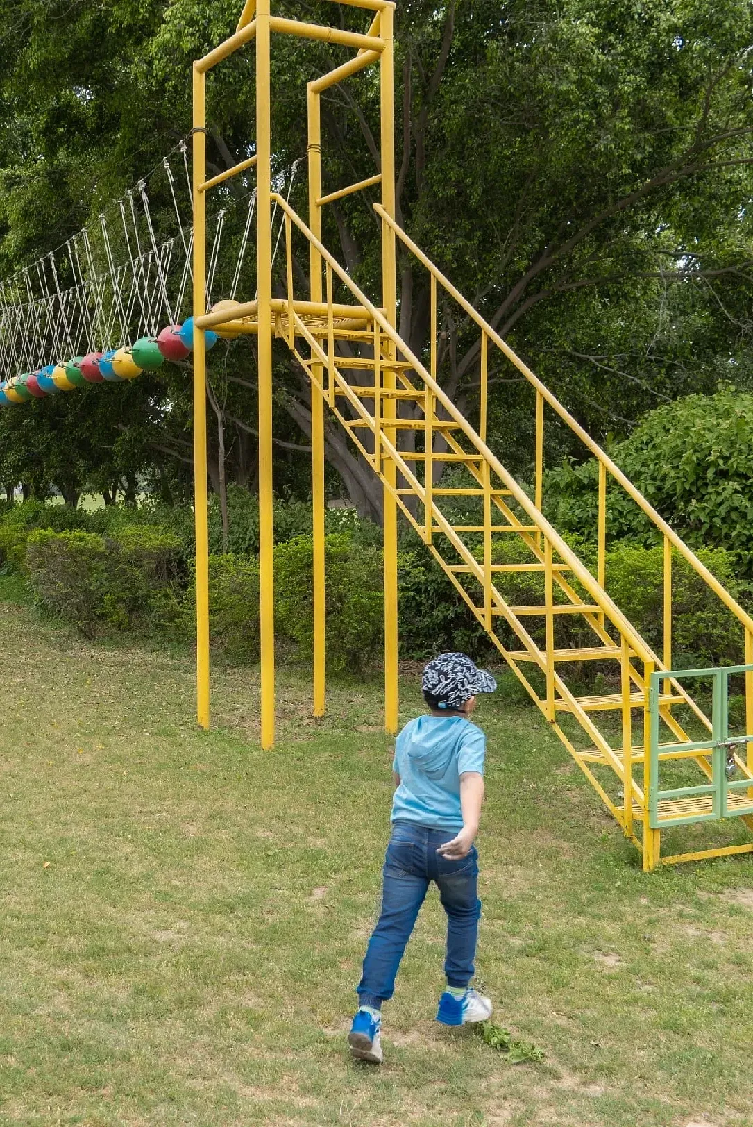 A child climbing a yellow metal slide structure in a grassy area at Karma Chalets.