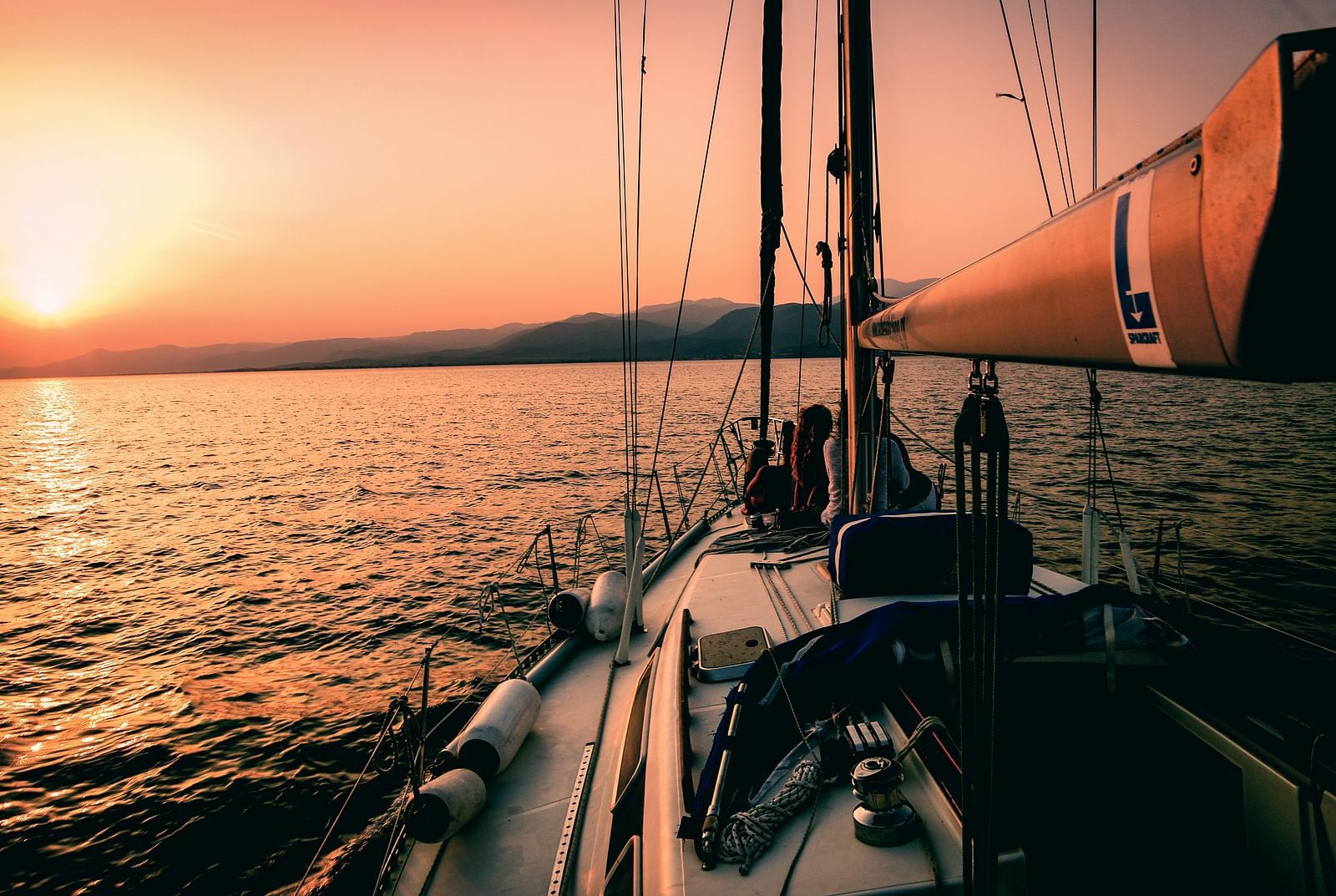 A sailboat sails on the ocean at sunset.