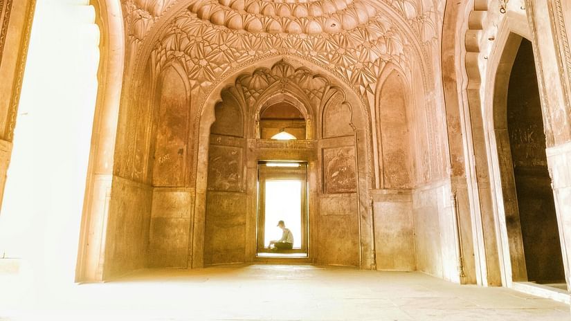 An interior shot of an ancient domed structure with intricate patterns on the ceiling, leading to a bright opening.