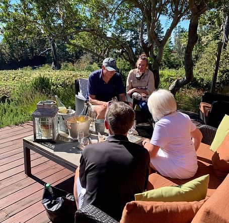 A small group in an outdoor gathering with drinks on a wooden deck