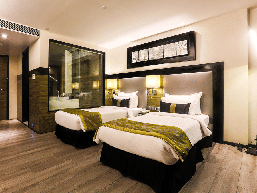Twin Executive Room at The Empresa Hotel, Mumbai featuring two beds, and an attached bathroom with bathing tub.