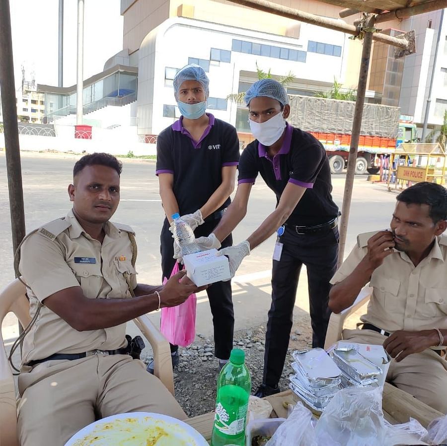 two staff members of giving a snack box to the police while posing for a picture - VITS Hotels & Resorts