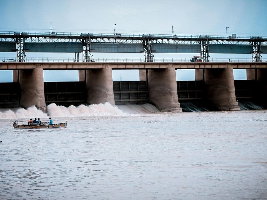 Image of an expansive dam with five gates and clean water flowing under it.