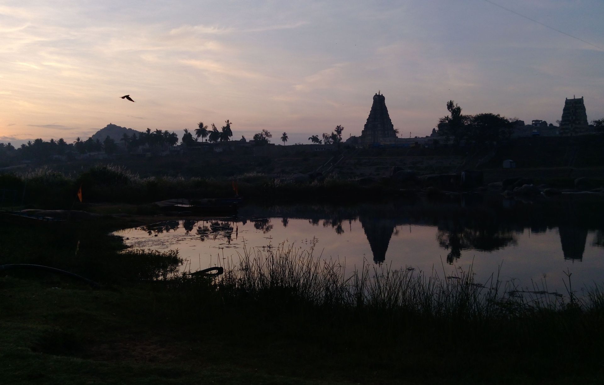 Hampi temples reflected in water at dawn.