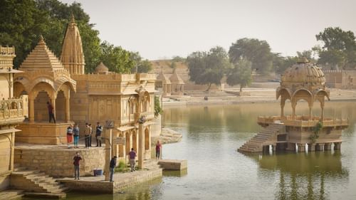 A far out view of a building in a waterbody with a cenotaph and another building on the banks