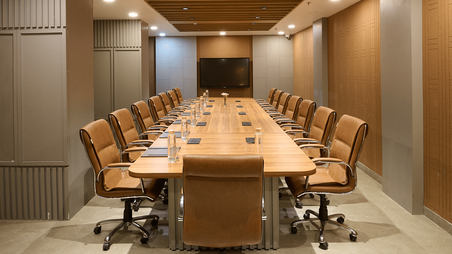 A conference room with a long wooden table, multiple chairs, and wood-panelled walls and ceiling | Voyage Eastin Suites