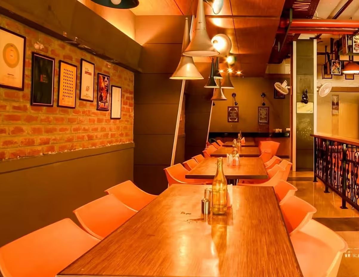 View of Mumbai Masala Restaurant with a warm ambience, wooden table and chairs, and stylish lighting- Max Hotel Prayagraj.