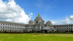 Facade of Vidhana Soudha in Bangalore with a lawn area in the foreground and the building with blue sky in the background
