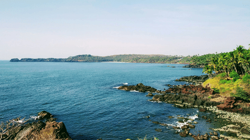 An aerial view of Cabo De Rama Beach with trees, greenery and rocks in view.