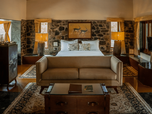 The Blackbuck Lodge - a tidy room with stone carved walls and posh bed