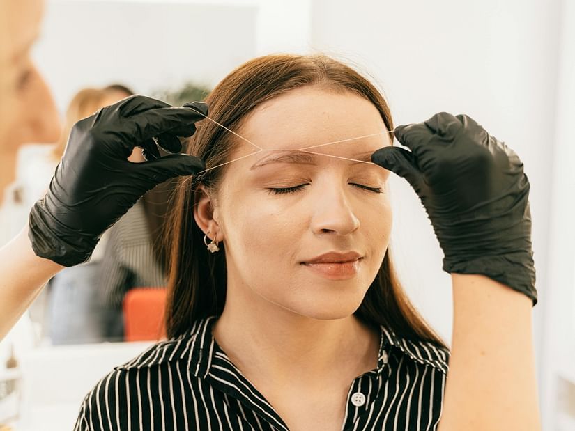 a woman getting her threading done in a salon by a professional