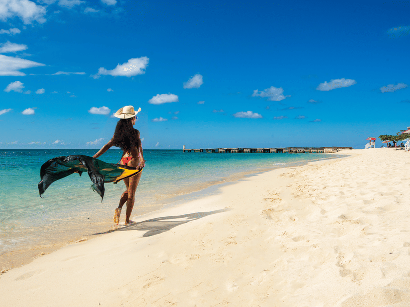 An image of a woman waling on a beach in her beach dress - S Hotel Montego Bay, Jamaica