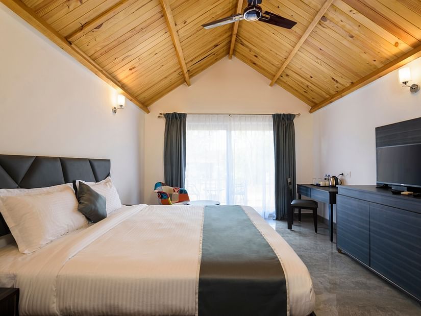 classic cottage room features a large bed, white walls and an LED TV