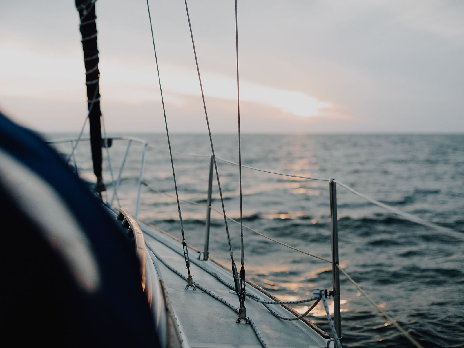A close up shot of inside a boat of the vast ocean with the sun shining in the distance.