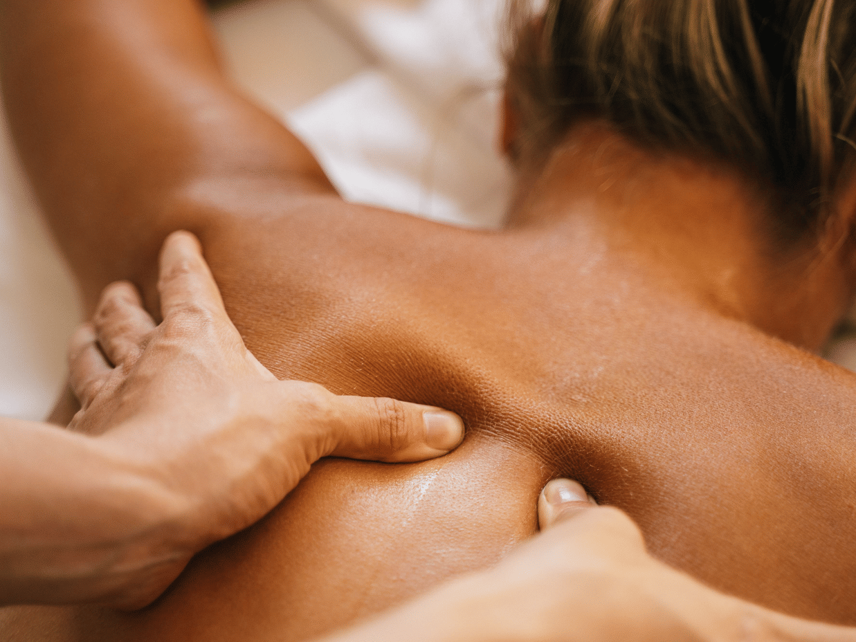 A close-up shot of a person massaging a woman's back by applying pressing with their fingers.