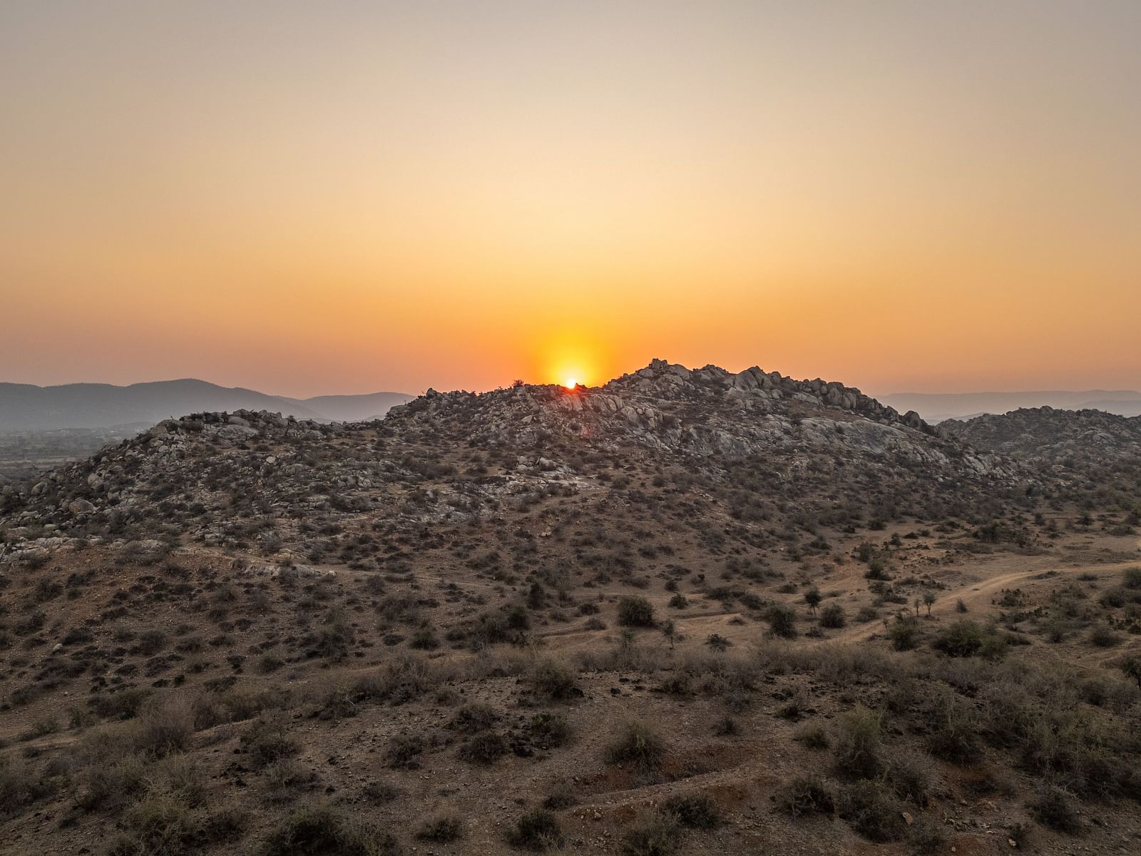 Image of sunrise taken from a far in a desert area