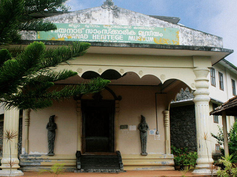 Old colonial-style building with arched windows and a green garden.