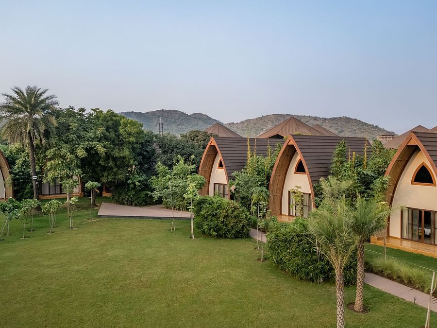 An image of a hut style villas amidst the palm trees in a resort - Ananta Spa and Resort, Ajabgarh