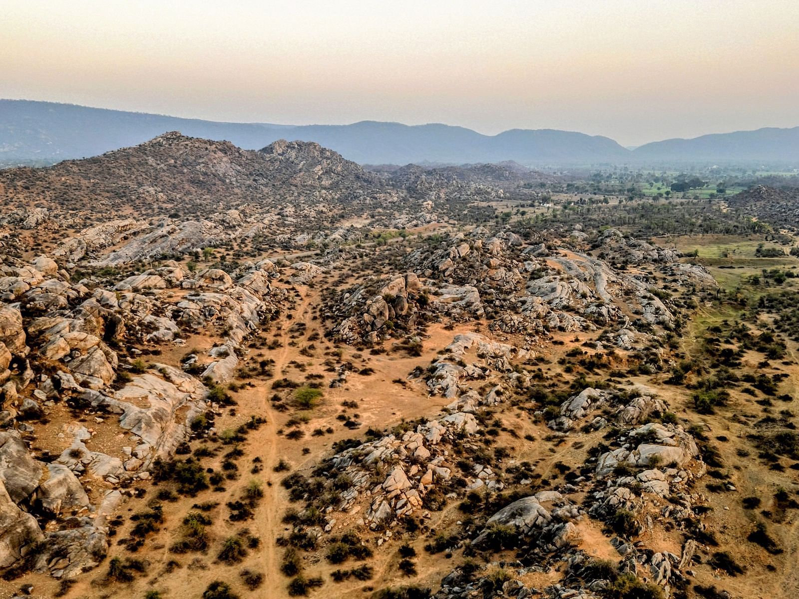 Aerial view of a rugged landscape with rocky outcrops and distant hills.