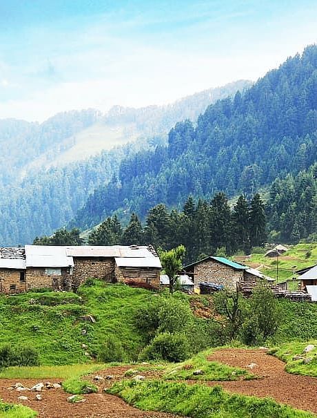 image of lush green landscape with a mountain range in the background with a clear blue sky