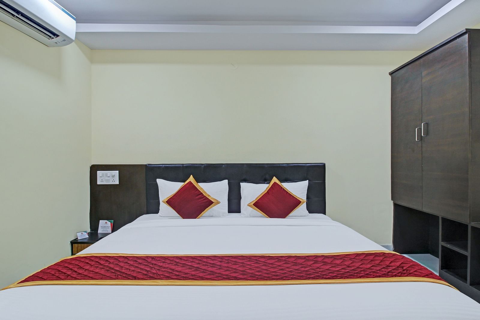 A hotel room featuring a double bed, air conditioning, wardrobe, and a minimalist design.