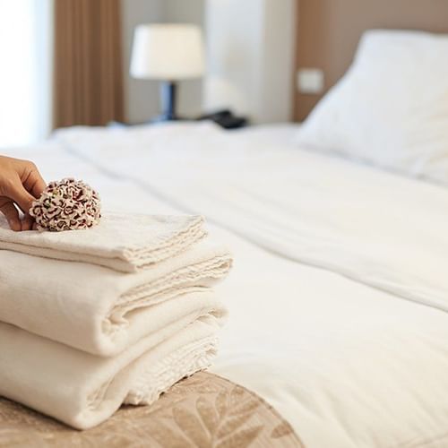 a lady folding towels on the bed - polo floatel kolkata
