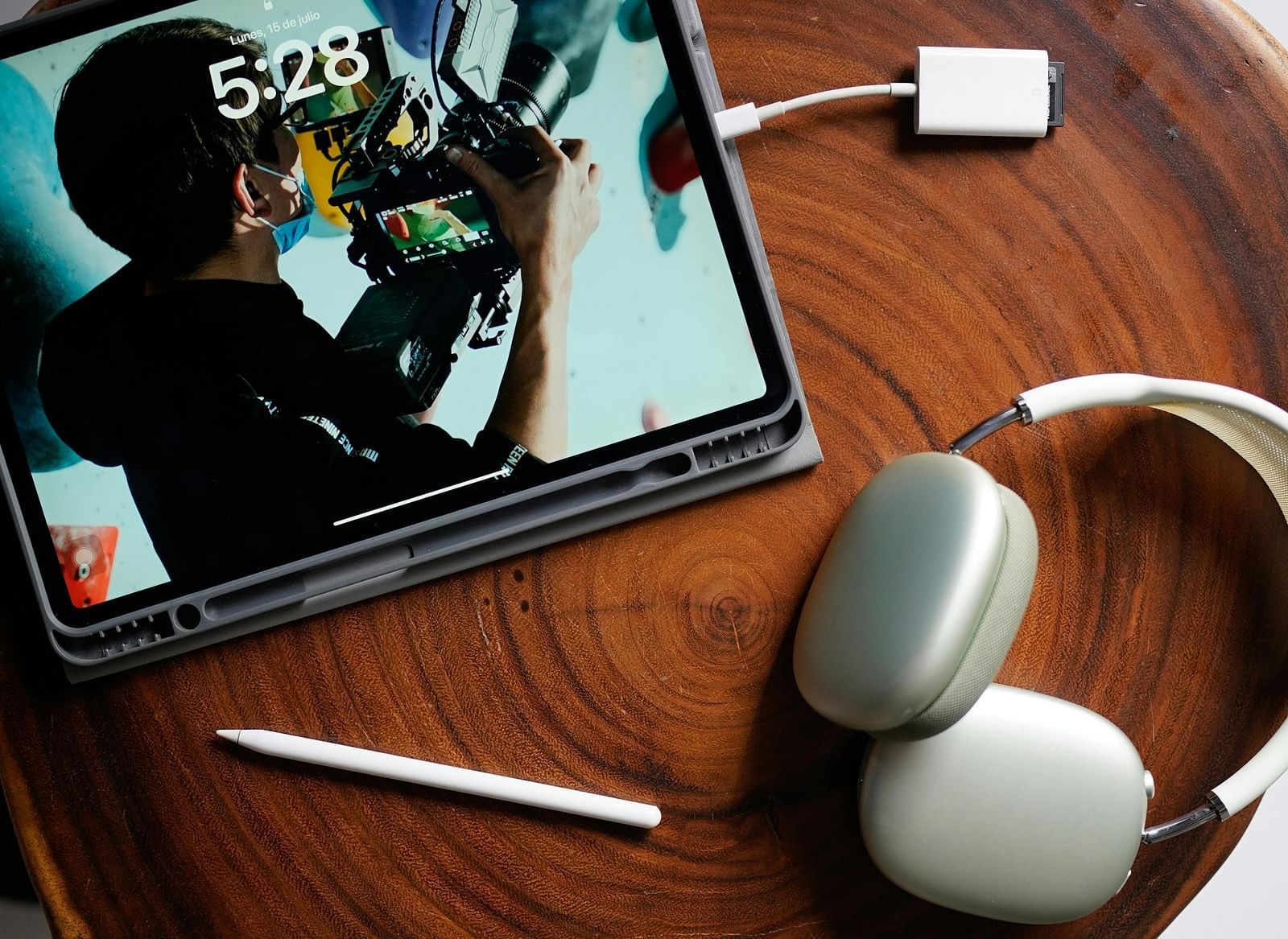 An image of a tablet, a pair of headphone,  charger and a stylus laid on a table