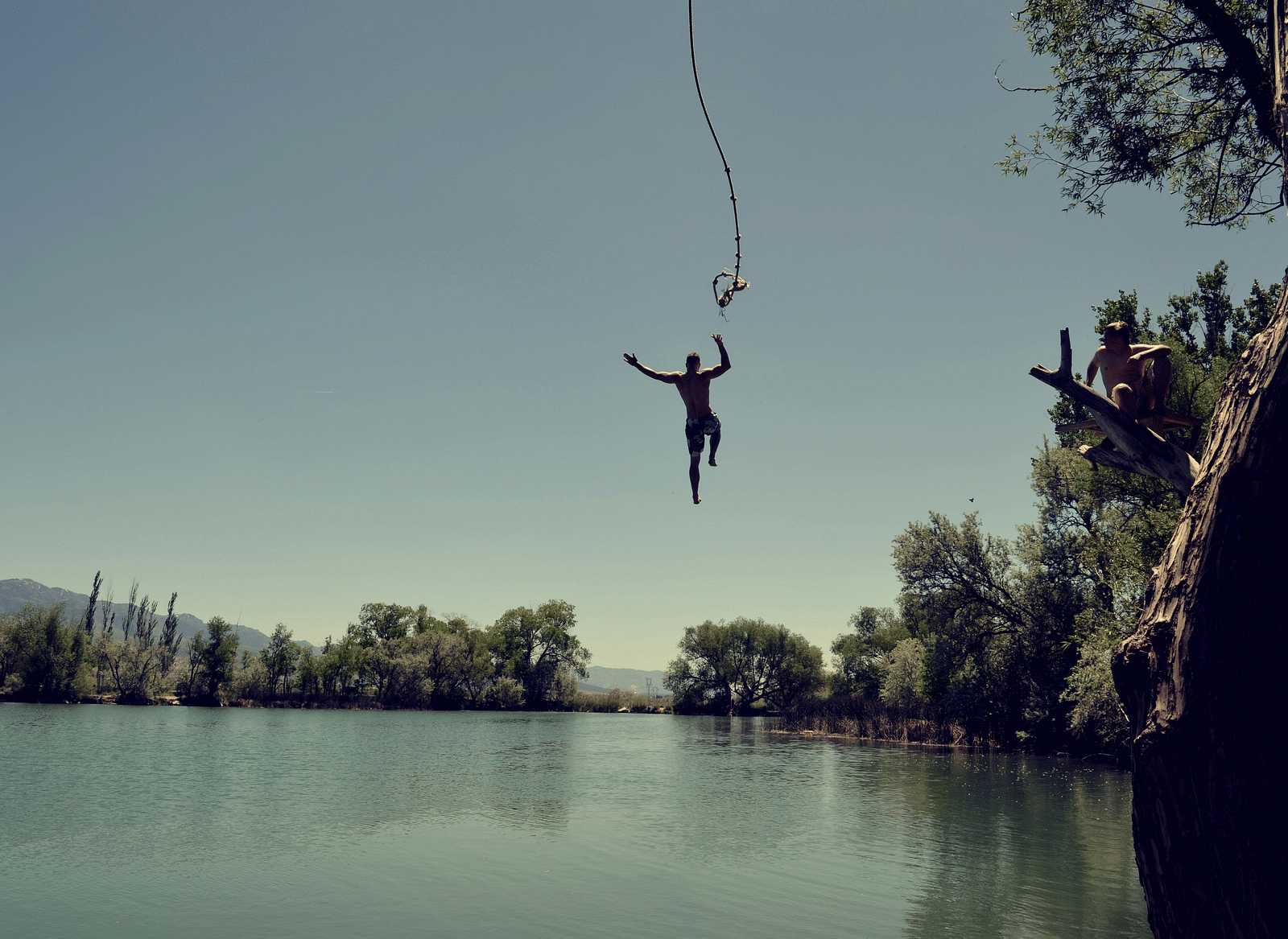 A person jumping from a deck into a pond.