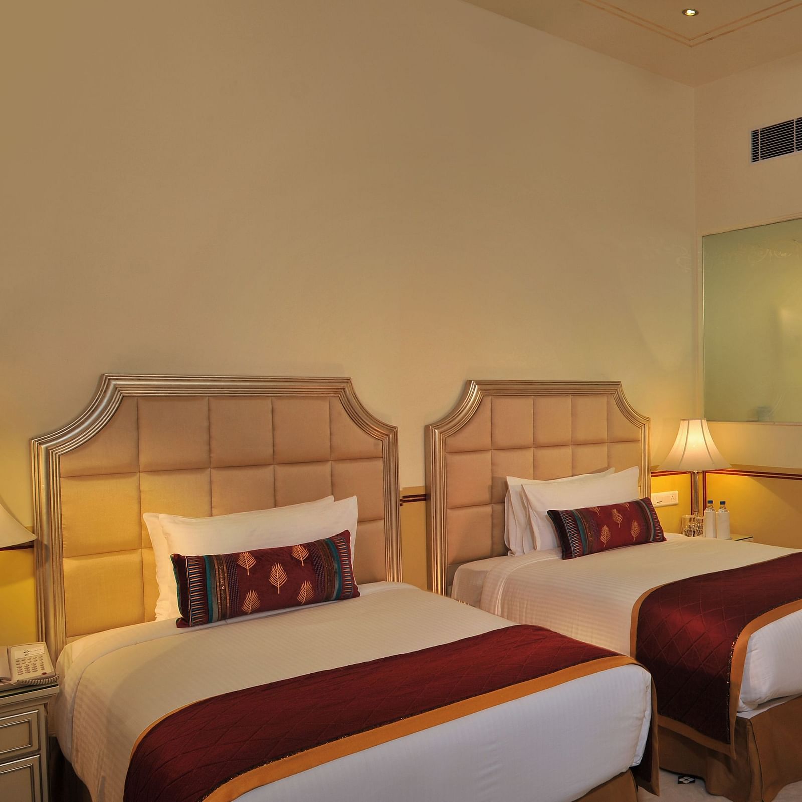 Image of a room with two beds and lamps on the sides of the bed at Rajasthali Resort & Spa Jaipur.