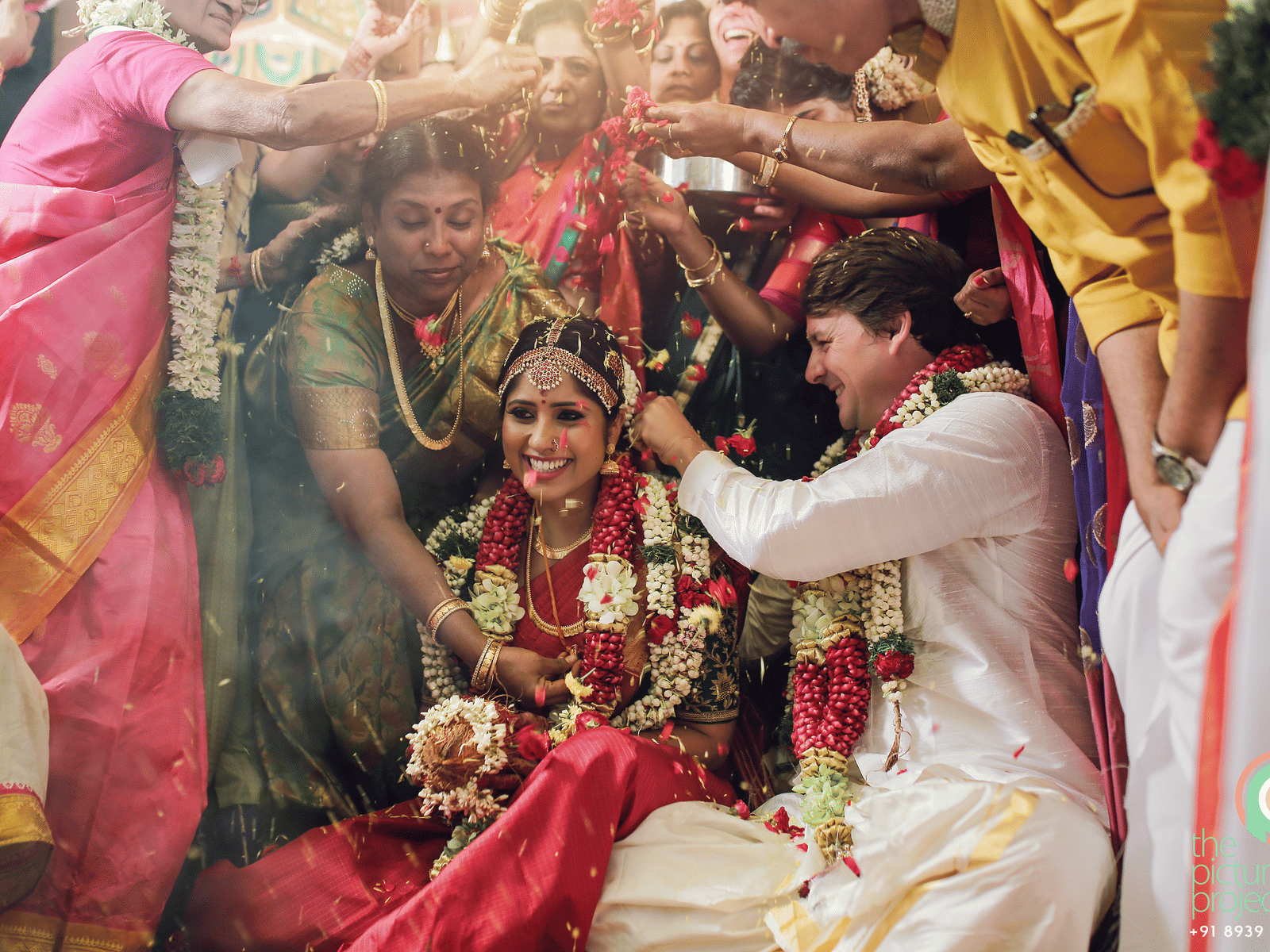 A traditional Indian wedding scene with the bride and groom surrounded by vibrant colours and floral decorations.