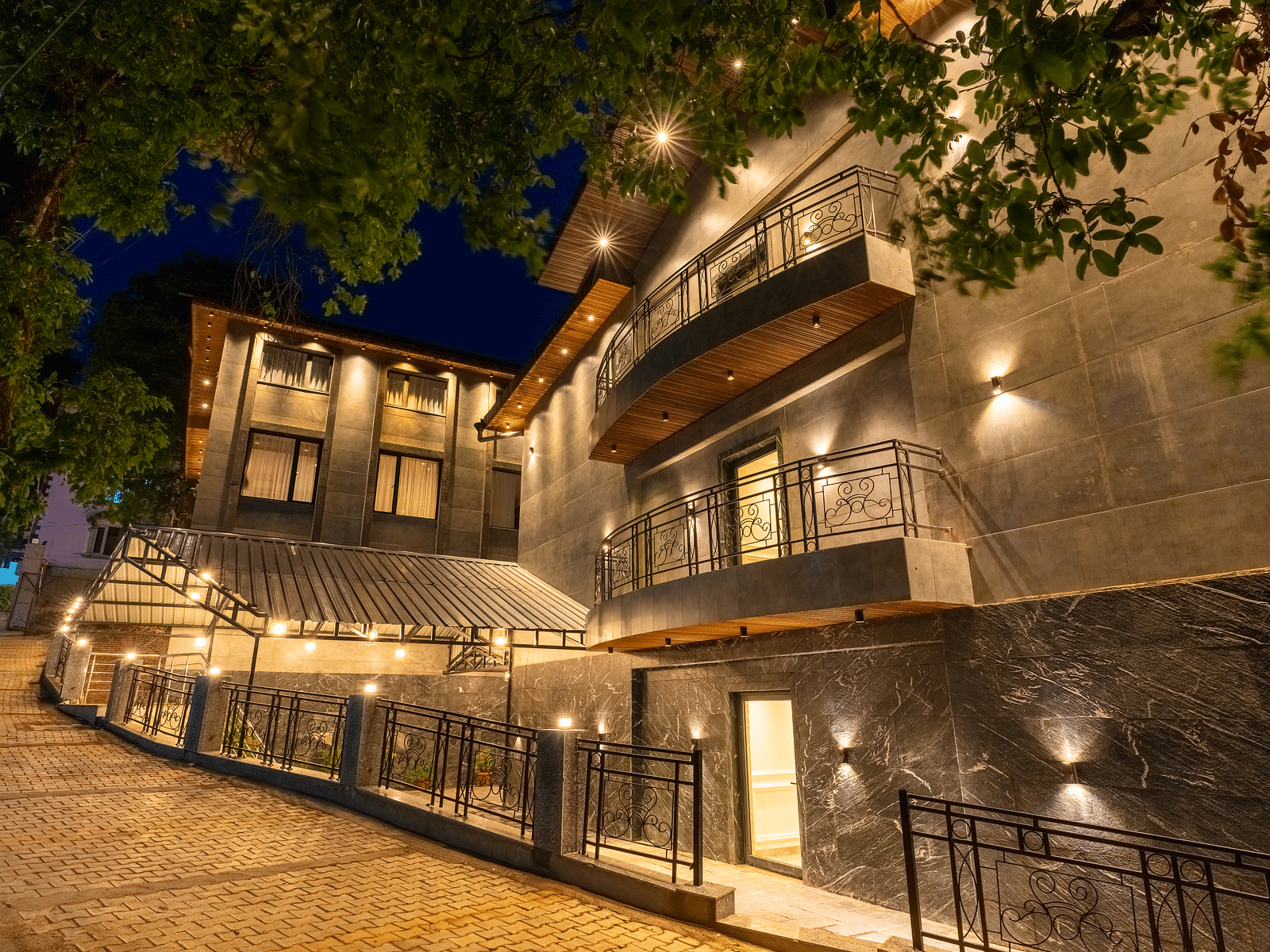 An image of a well lit facade with trees around at Bedzzz Xclusiv Ikshana Luxe, Nainital