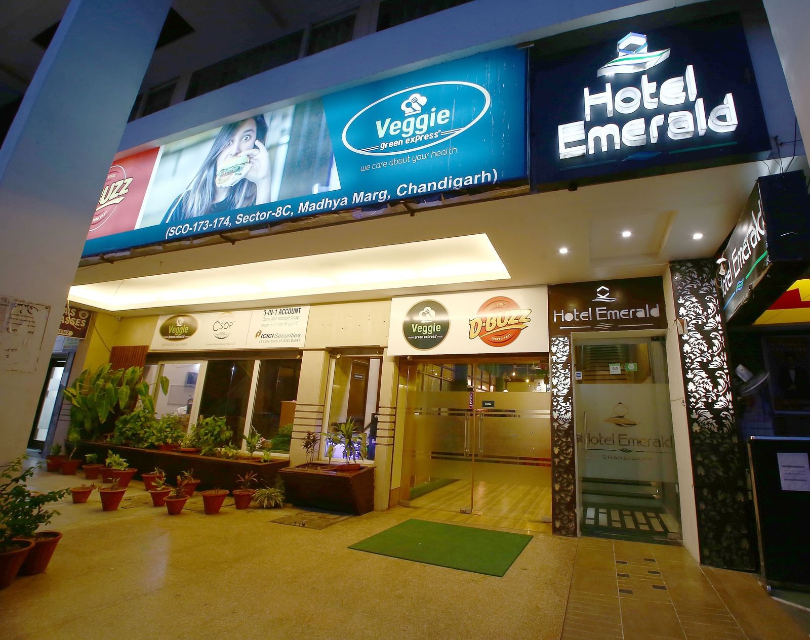 Illuminated entrance of Hotel Emerald at night with hotel signage