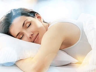 A person sleeping on a bed, resting their head on a pillow and a hand under it