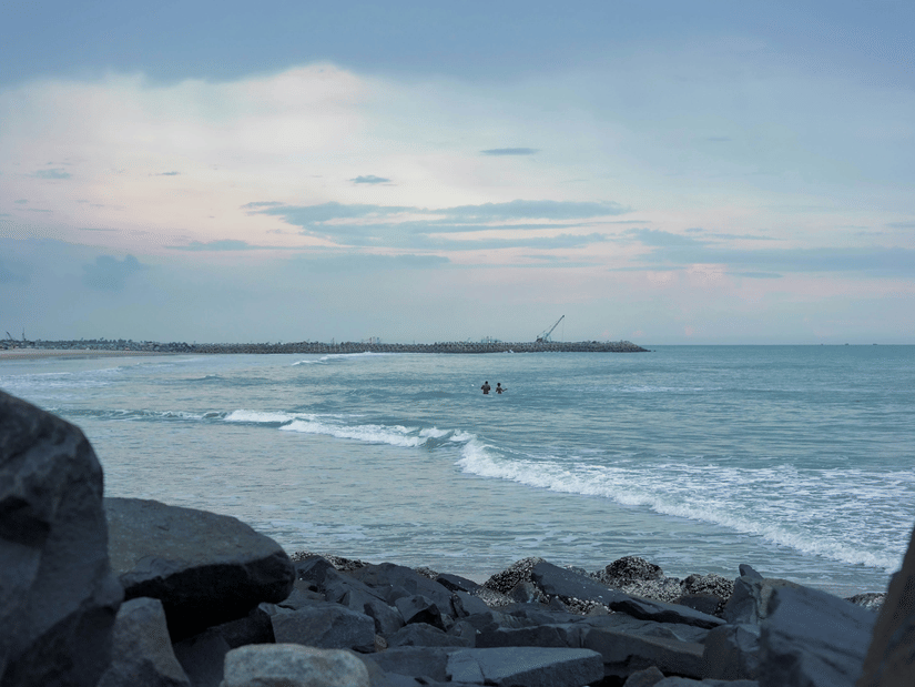 Gentle waves roll towards the rocky shoreline beneath soft afternoon light by sea