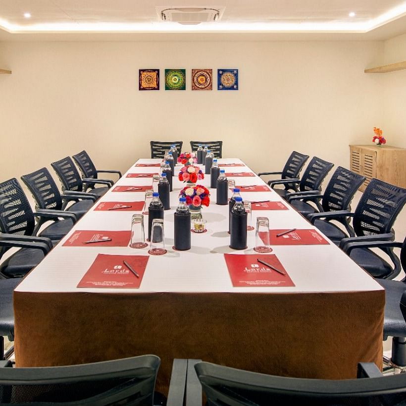 a boardroom seating arrangement with ceiling lights and a corner shelf