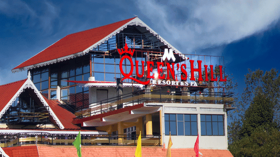 Mount Queens Hill Lake Resort & Spa in Mirik featuring a sloped red-roof structure with large glass windows, terrace seating, and vibrant hillside surroundings | A unit of Mount Hotels in North Bengal