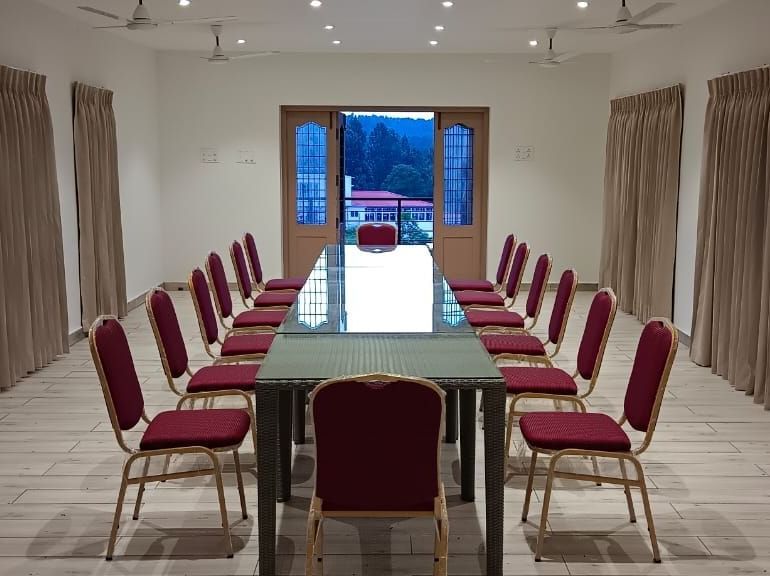 Front-view shot of the Green Park hall with chairs and tables arranged in boardroom setting at WOW Naturefull Resorts.