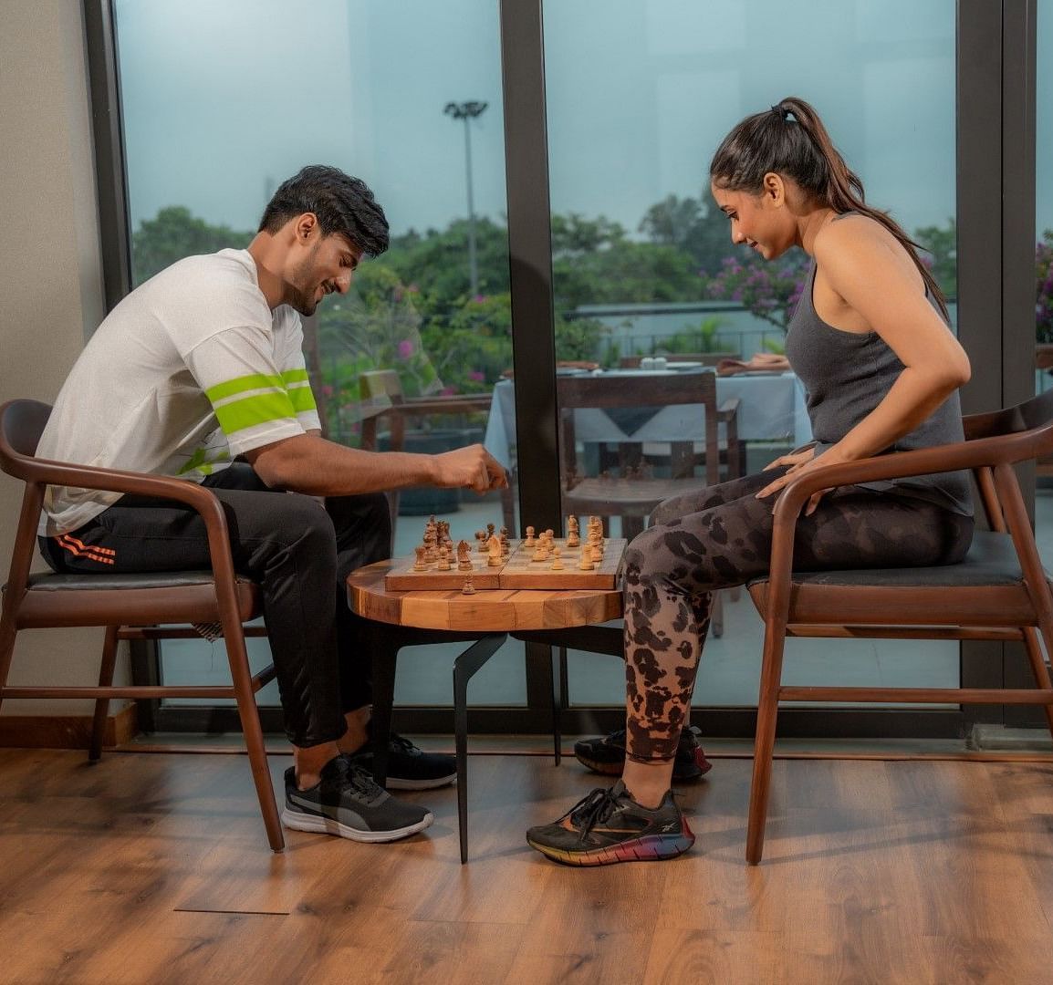Two people playing chess in a well-lit room with French windows