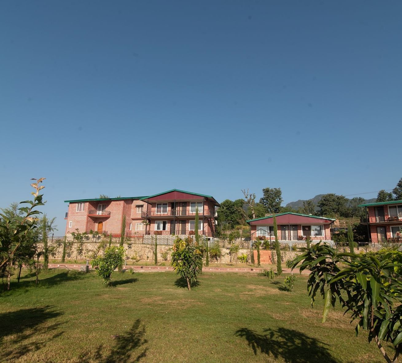 Facade of Neer ganga Resorts with a lush green lawn in the front