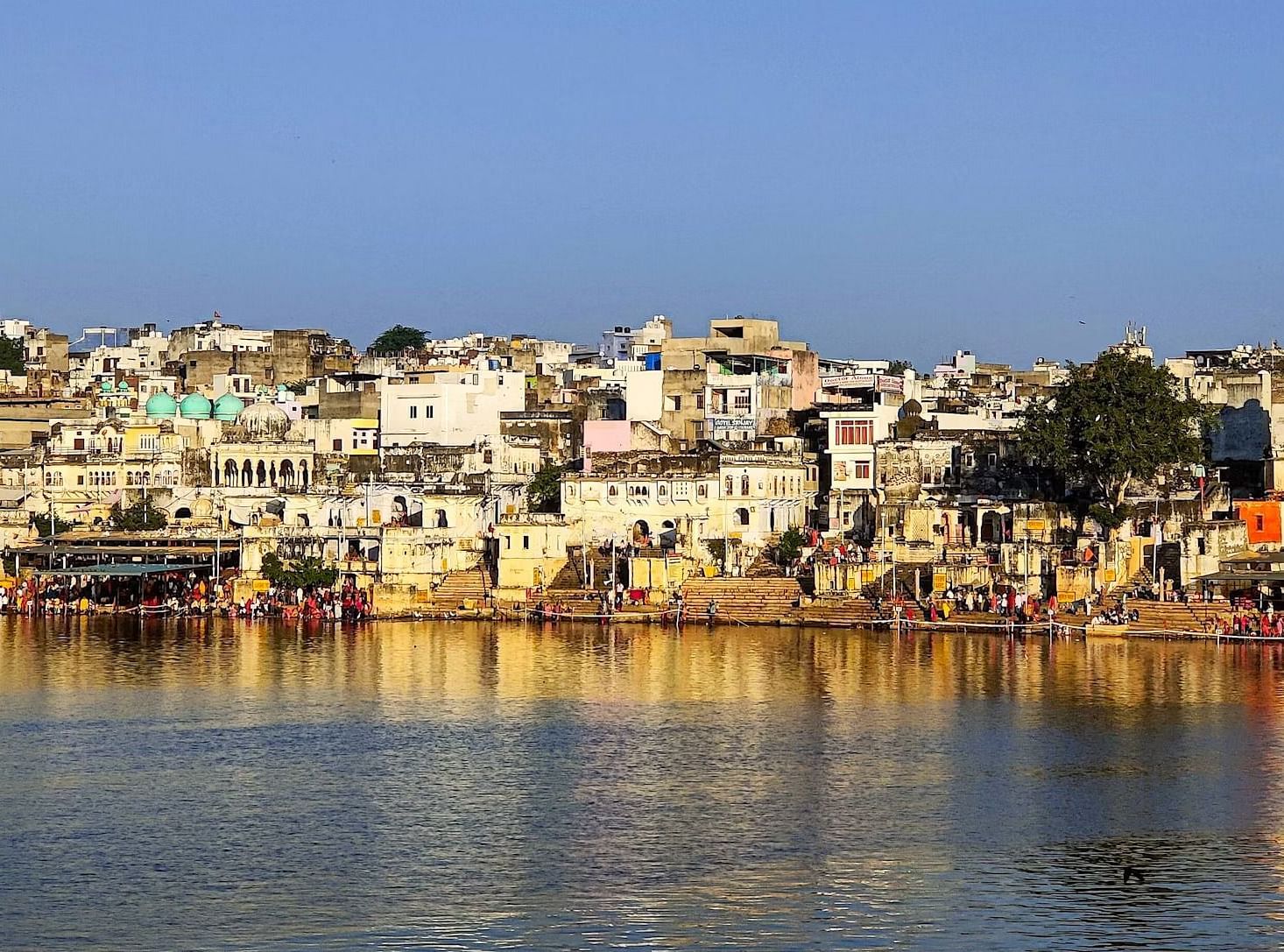 Buildings line the shore of a body of water under a clear sky.