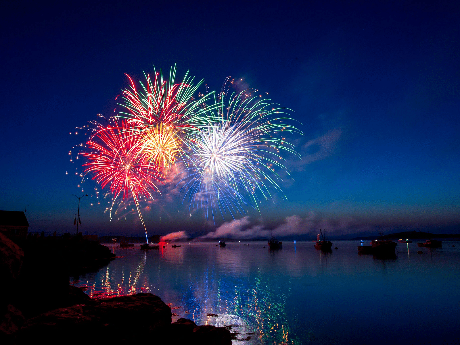 Colorful fireworks reflected over a calm body of water at night