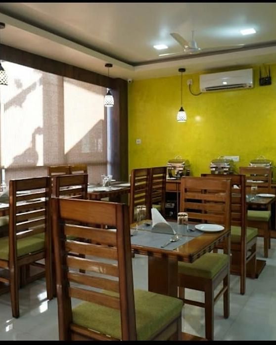A brightly lit dining space with wooden tables and chairs, perfect for relaxed meals - Pemaling Lords Eco Inn Guwahati