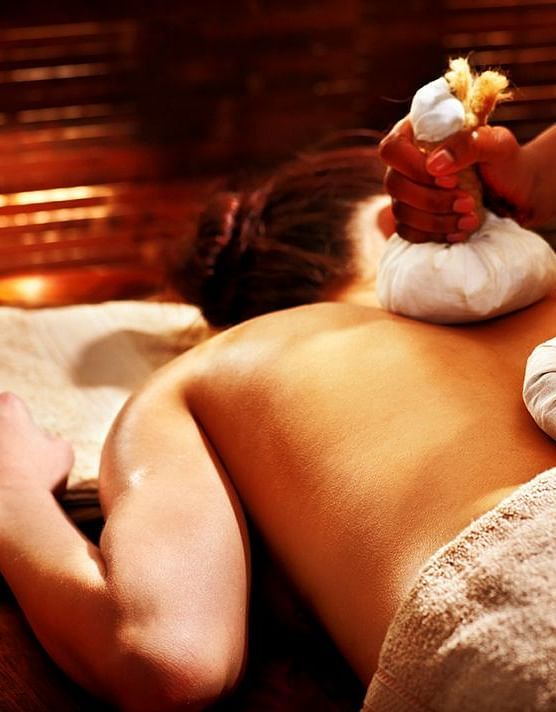 a woman getting a massage while lying down on a massage table - neer ganga Resorts